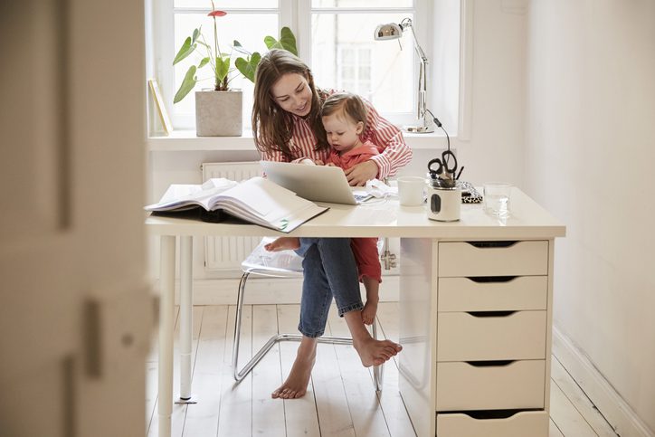 Martinson & Carter, CPAs, PA | woman with a baby in her lap at a desk looking at her laptop and smiling